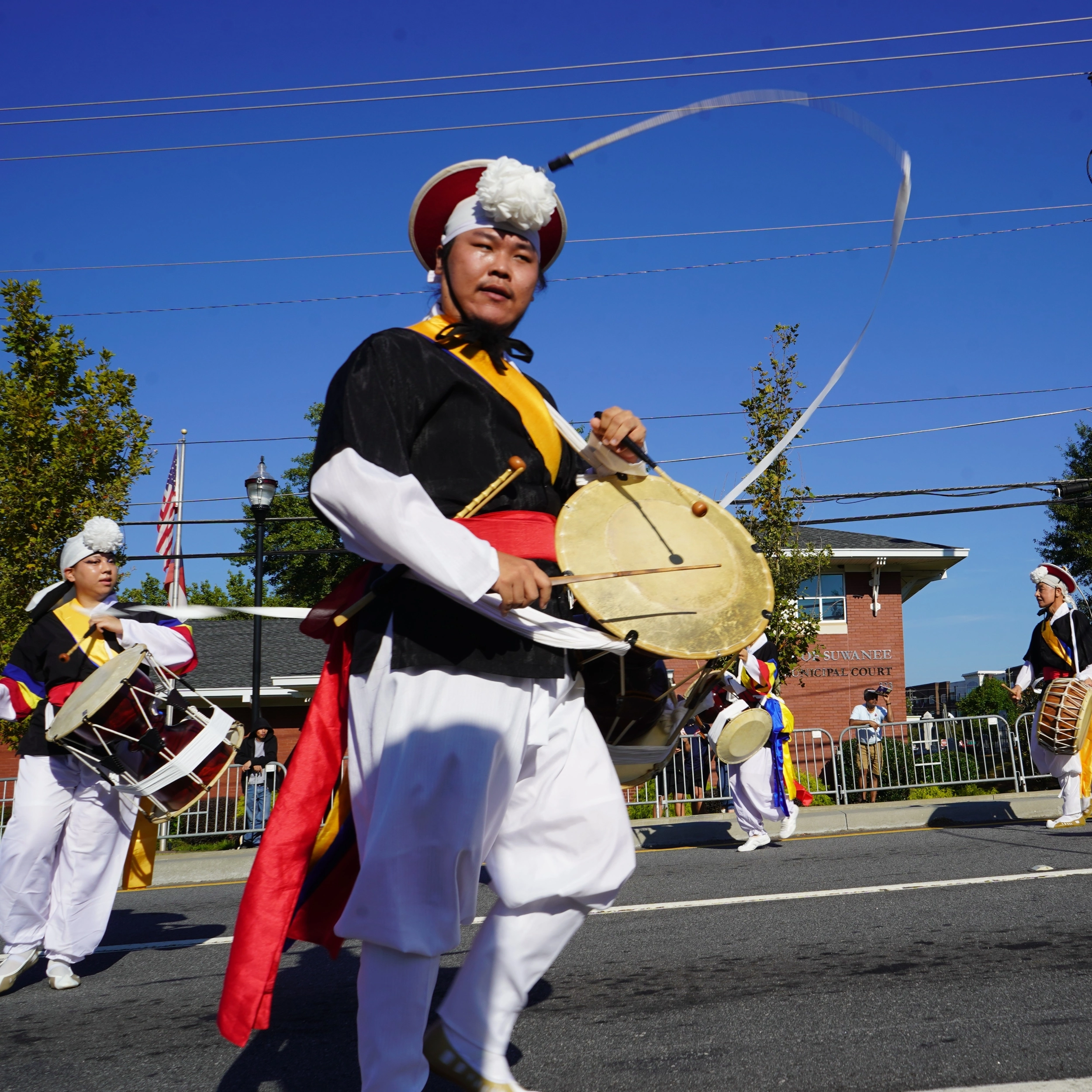 Performers in traditional Korean attire play drums in the Suwanee Fest parade.